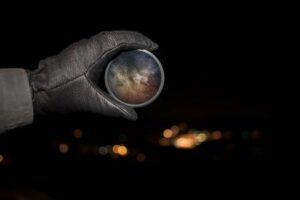 Gloved hand holding up a spyglass in the night