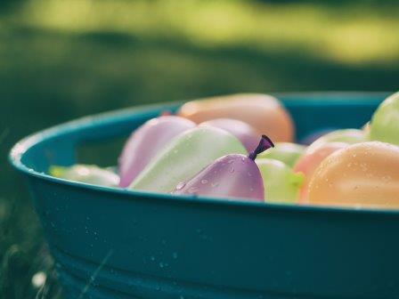 Colorful water balloons in a bucket outside